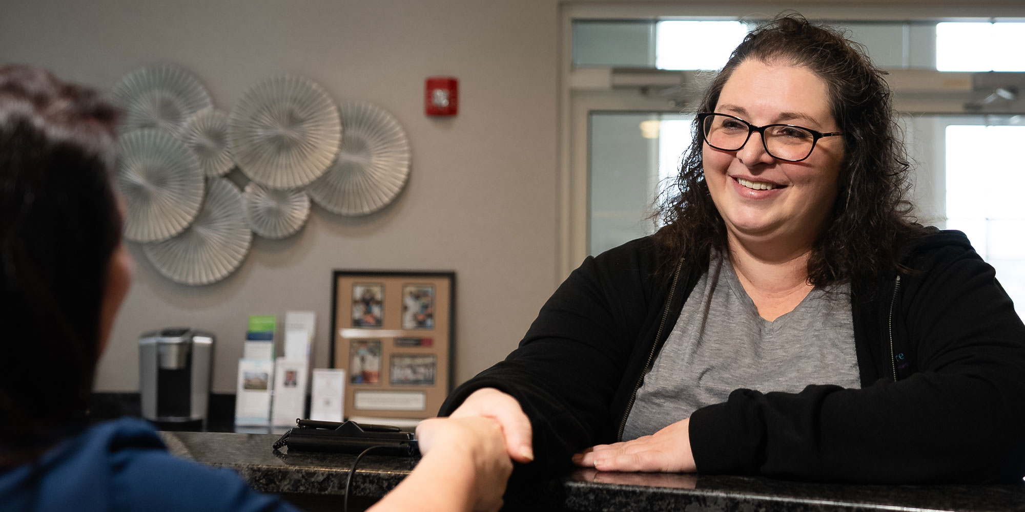 team member saking patients hand greeting them into the dental office