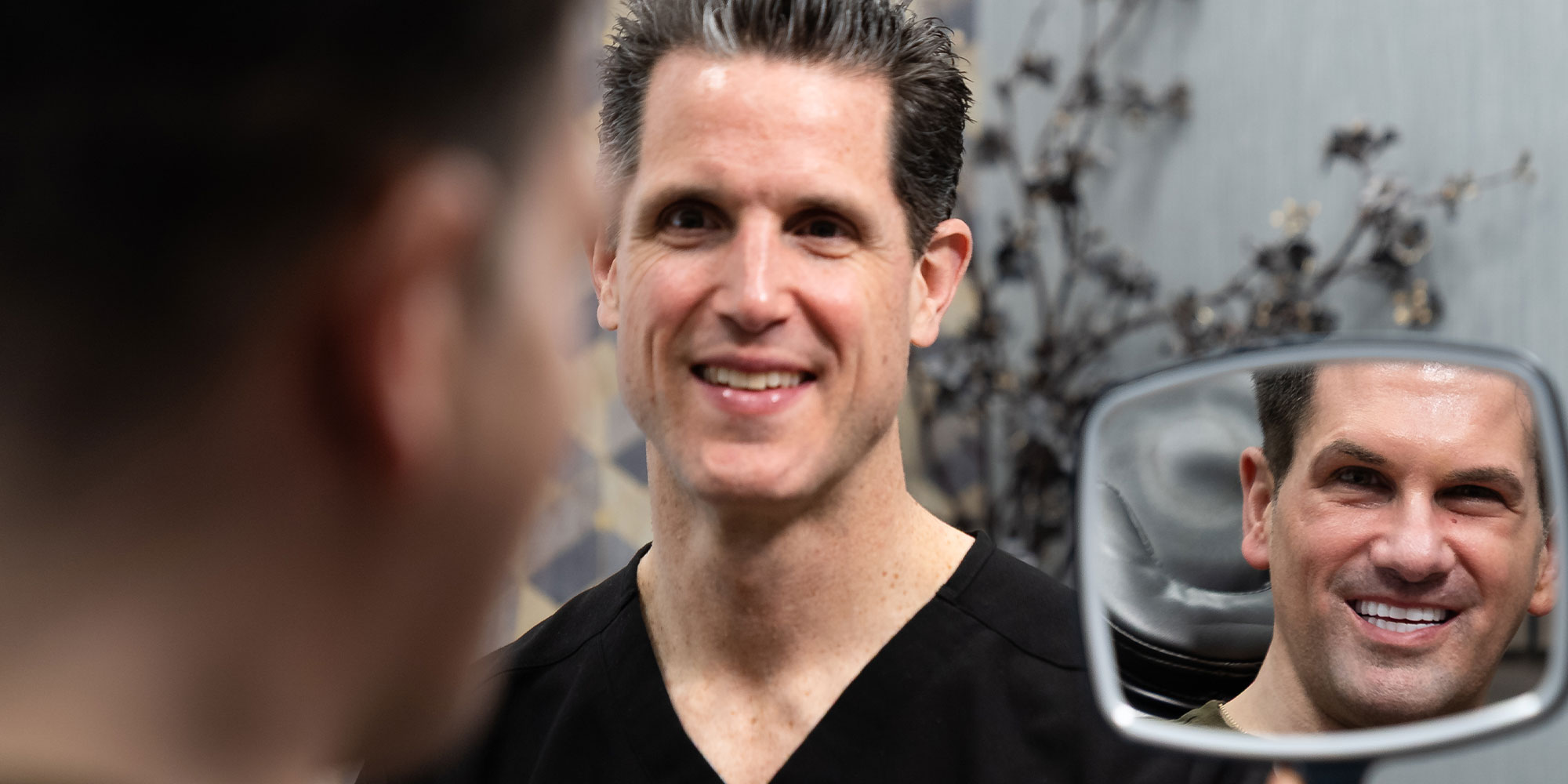 doctor holding up mirror so patient can see their brand new smile