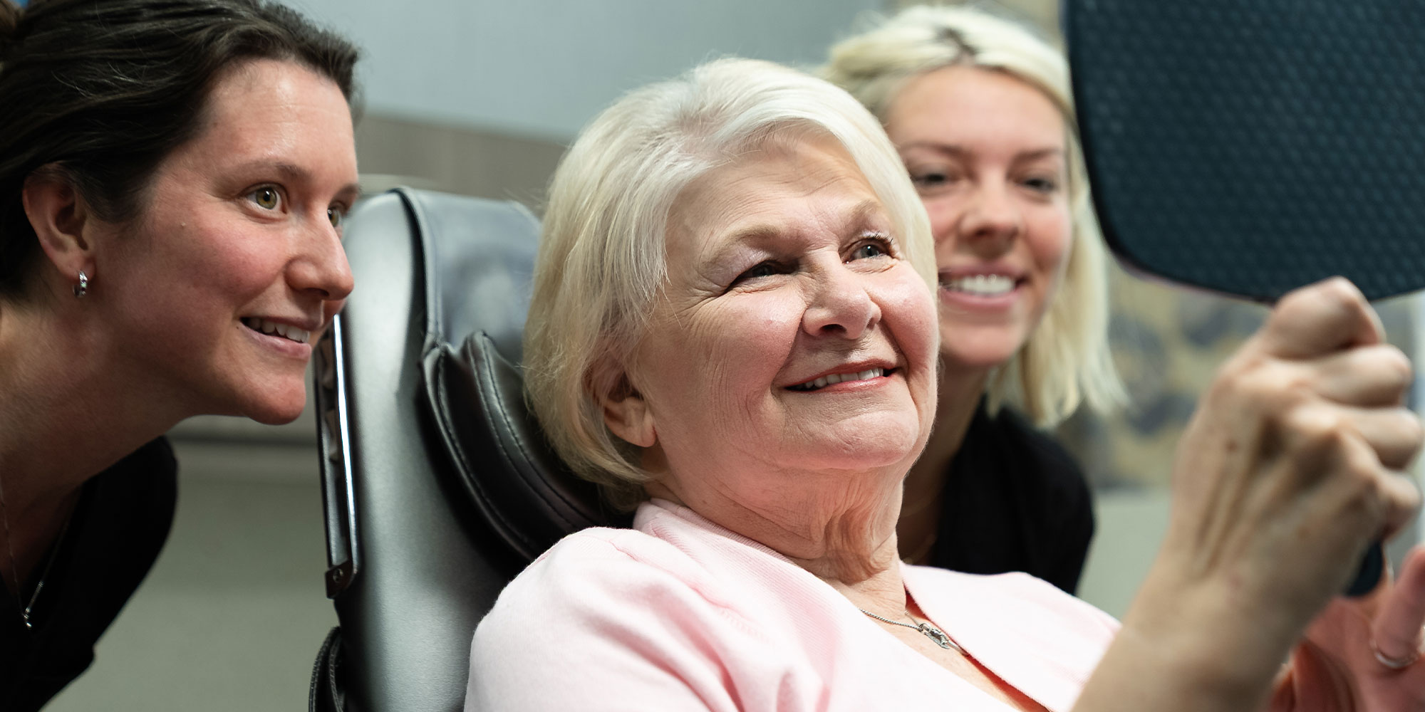 team member and patient looking into mirrors smiling