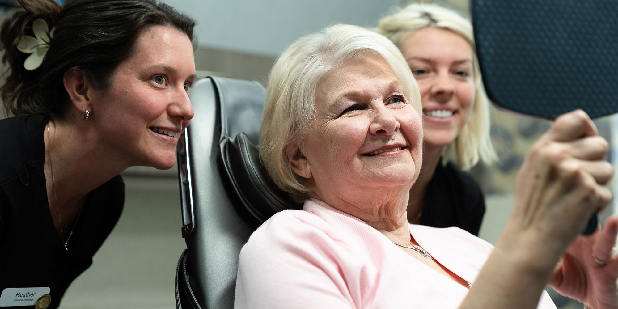 WOman looking at her new teeth in mirror